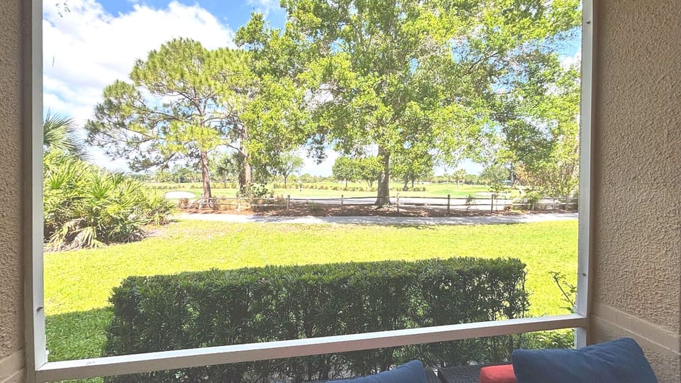 Peaceful outdoor view overlooking green space, mature trees, and a scenic walking path.