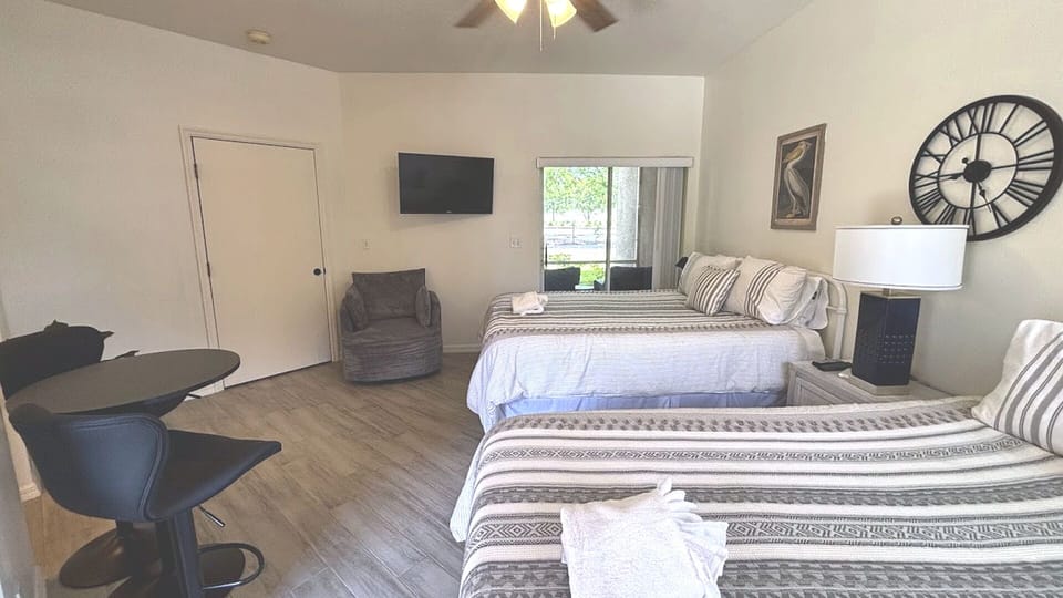 Spacious bedroom with two comfortable beds, TV, sitting area, and a clean, welcoming setup.