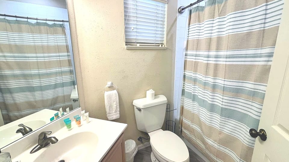Clean bathroom with vanity, toilet, tile flooring, and a tub/shower combination.