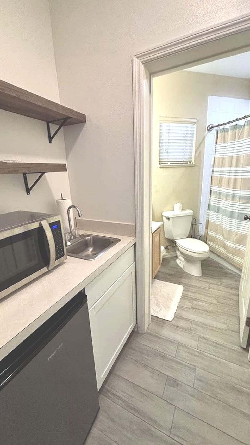 Convenient kitchenette area with sink, microwave, mini fridge, and easy access to the bathroom.