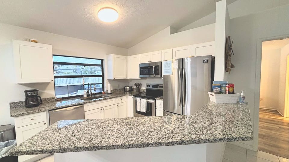 Updated kitchen with granite countertops, stainless steel appliances, white cabinetry, and plenty of prep space.