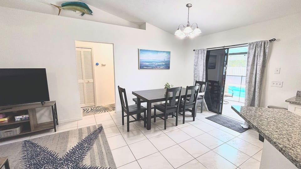 Dining area with table seating, tile flooring, and direct access to the screened pool patio.