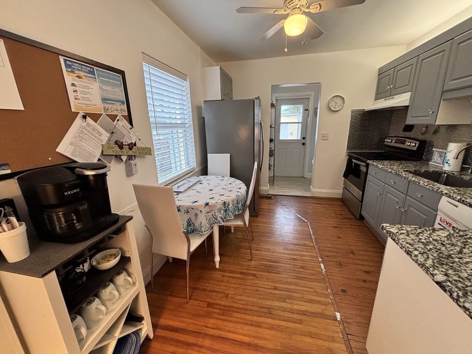 Kitchen and dining area with wood flooring, granite counters, coffee station, and a cozy breakfast table.