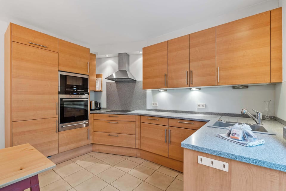 Spacious kitchen with oven, stove, dishwasher, microwave, cookware, and bright views toward the greenery
