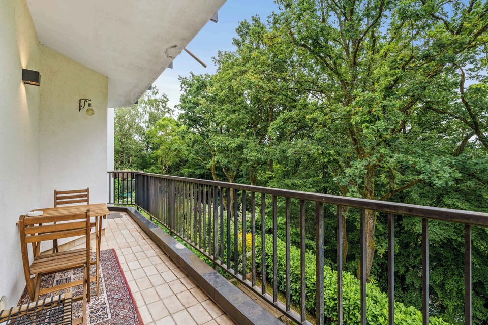 Private balcony surrounded by trees, perfect for morning coffee or a peaceful break during your Luxembourg stay