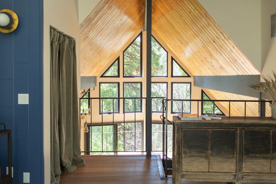 The loft opens to soaring A-frame windows of the great room, and the skylights make you feel as if you've woken inside the trees.
