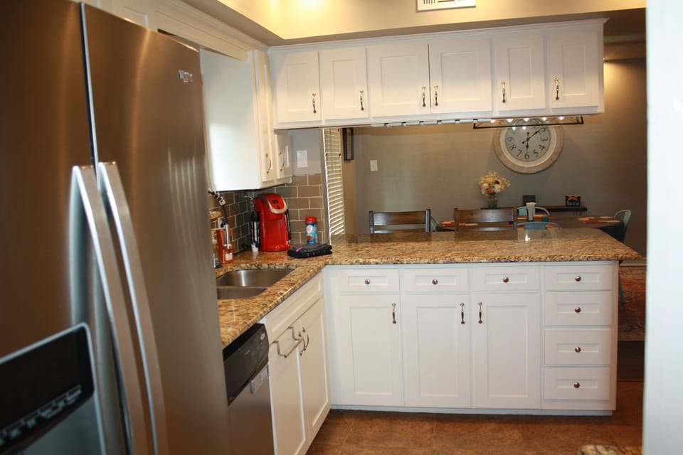 Kitchen bar top with coffee maker. Dining area behind. 