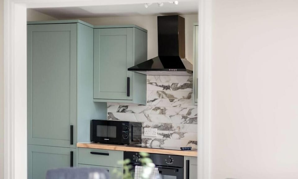 Gather around the elegant glass-top dining table, comfortably set for four guests. Surrounded by modern upholstered chairs in soft grey tones, this bright and inviting space is perfect for enjoying breakfast, sharing a meal, or planning the day ahead