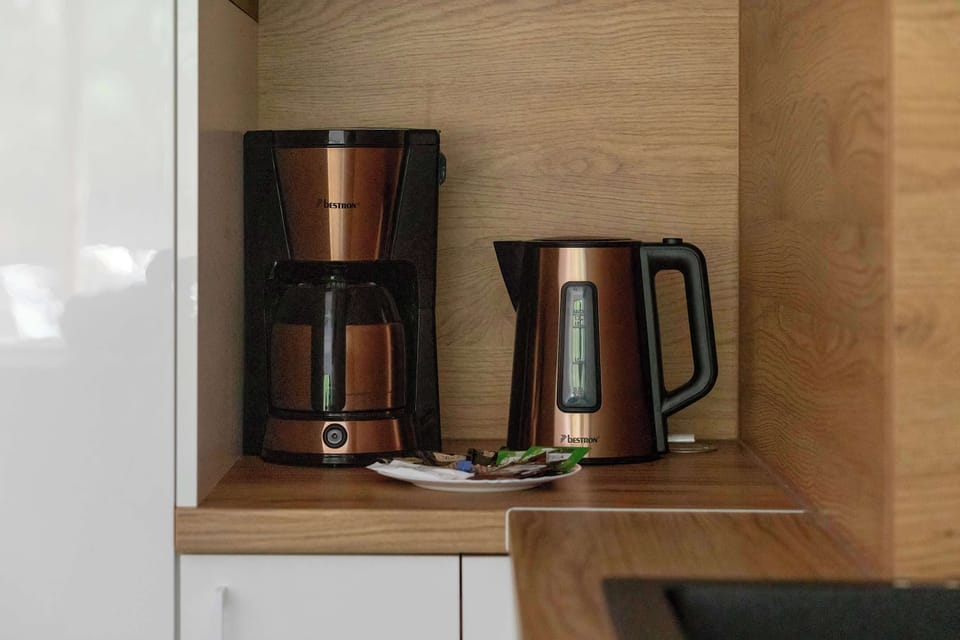A coffee maker and electric kettle placed inside a wooden kitchen cabinet. The appliances are neatly stored and ready to use.