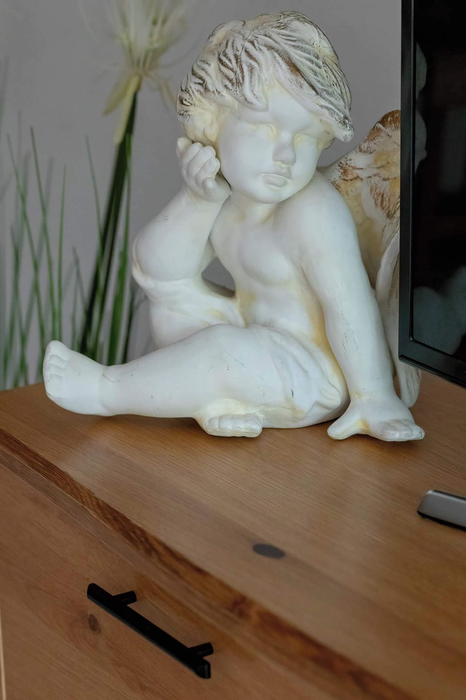 A decorative white angel figurine placed on a wooden shelf. The close-up highlights a charming interior detail.