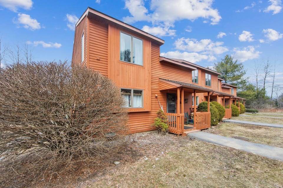 Well-maintained exterior view of the multi-level townhome featuring charming rustic wood siding.