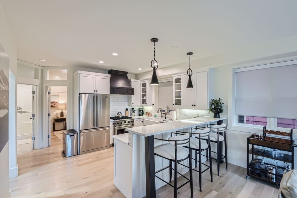 Whip up meals and gather with ease in this bright designer kitchen featuring quartz countertops, stainless steel appliances, and bar seating for four.