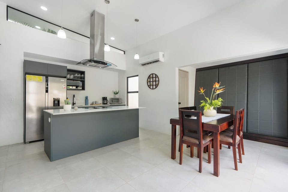 The open concept kitchen features a spacious counter bar and dining area made for socializing. Ideal for hosting a private chef at this luxury Playa Langosta vacation home.