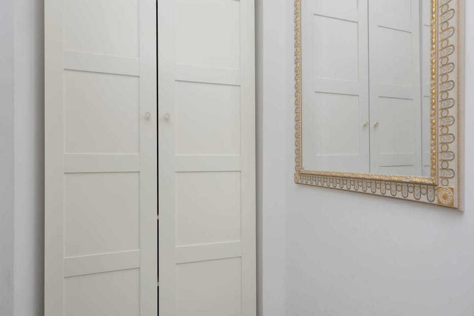 A hallway with white doors and a decorative wall mirror. The bright interior feels clean and elegant.