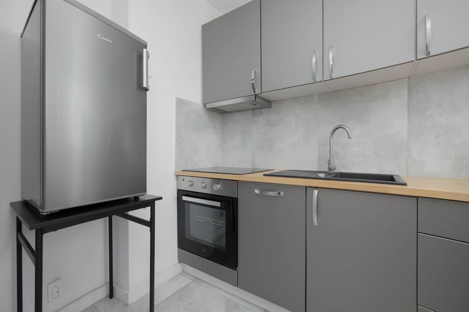 Another view of the kitchen featuring a refrigerator, oven, and sink. The design is clean and contemporary.