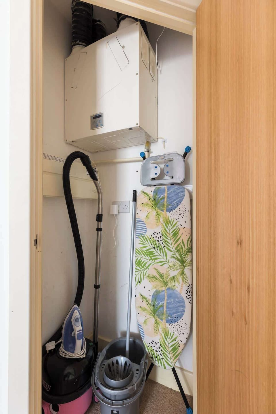Utility cupboard including iron with iron board, hoover and mop. 