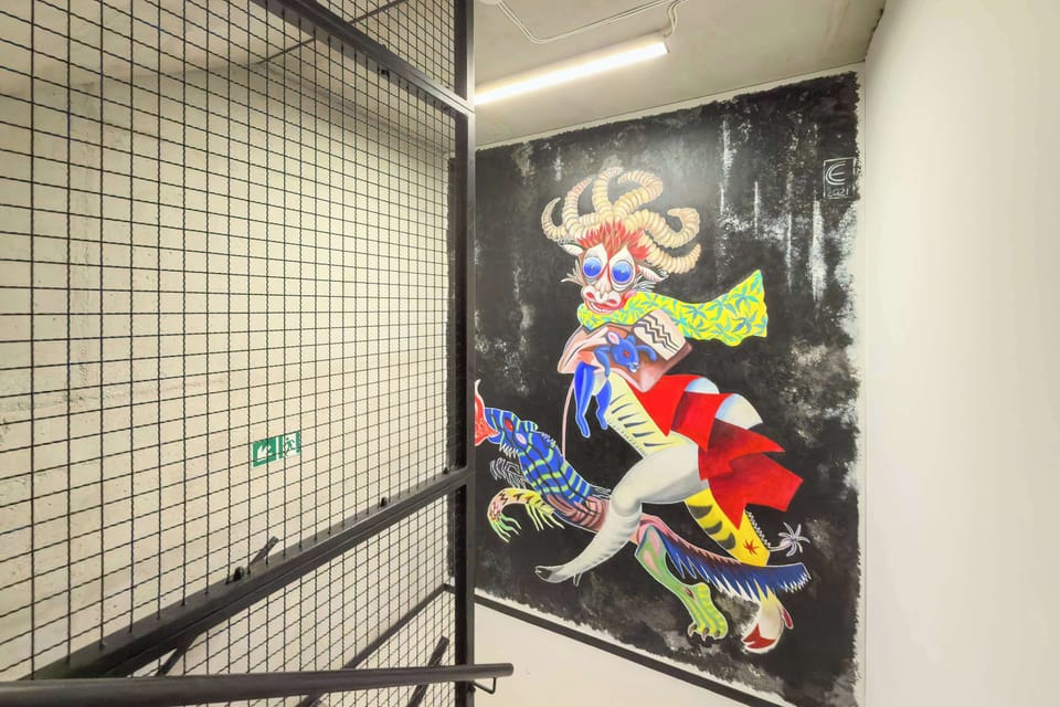 A stairwell wall features a colorful mural with bold artistic elements. Industrial-style railings add character to the shared space.