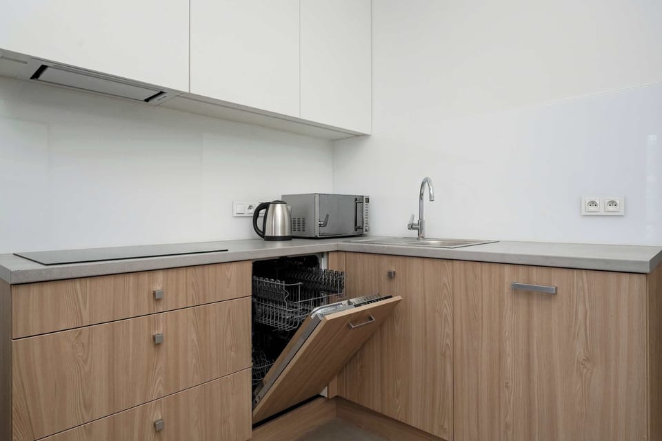 A kitchen corner highlights wood cabinetry, light countertops, and integrated appliances. Clean lines give the room a modern appearance.