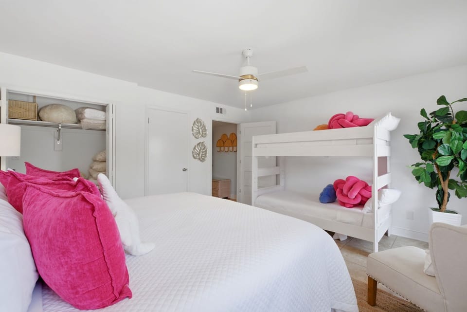 North Lost Key Landing B2- A bright, cheerful bedroom perfect for families—your group can spread out with both a cozy queen bed and white bunks, all bathed in natural light beneath a refreshing ceiling fan.