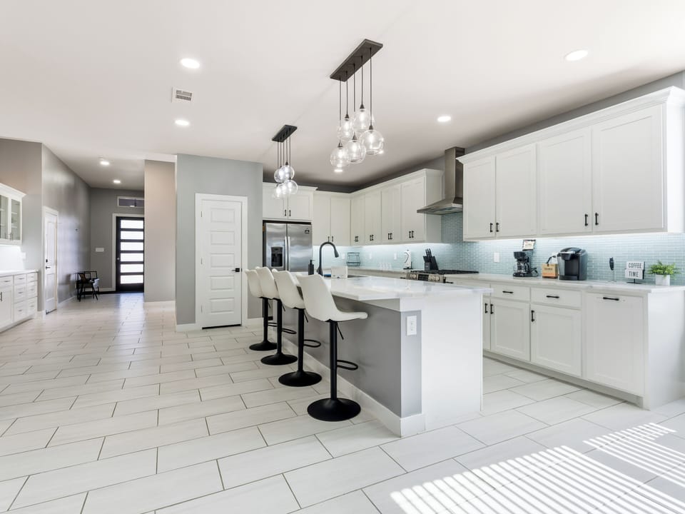 Your culinary retreat awaits with sleek white cabinetry, gleaming countertops, and modern fixtures. Gather at the island for coffee or conversations, surrounded by chic pendant lighting and a bright, open layout.