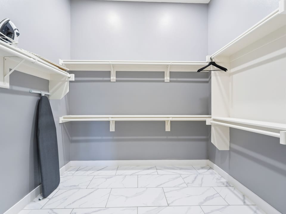 A spacious walk-in closet offers generous shelving and hanging space for all your belongings, with a convenient iron and ironing board ready for your use.