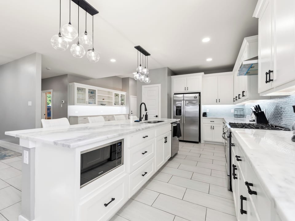 Your dream kitchen awaits with gleaming marble countertops, stainless appliances, and a chef-ready gas range. Prepare meals beneath stylish pendant lights in this spacious, modern culinary haven designed for your comfort.