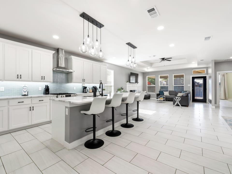 Your culinary haven features gleaming white cabinetry, a spacious island with bar seating, and modern pendant lighting—perfect for gathering with friends or cooking your favorite meals in style.