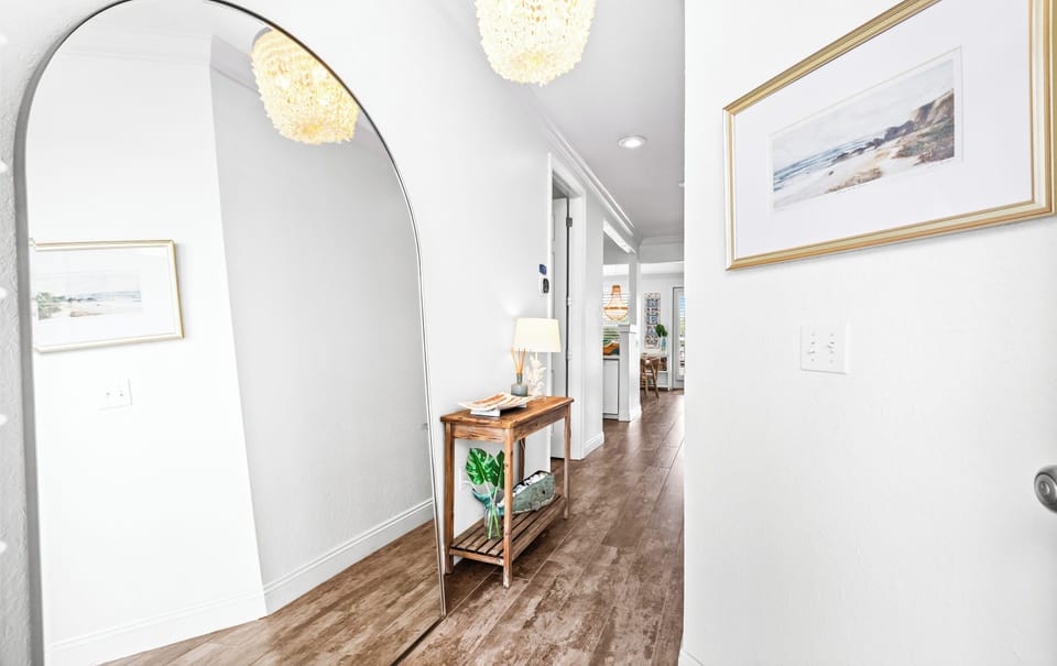 A bright hallway welcomes you with coastal artwork and warm wood floors, setting a relaxed tone for your stay.