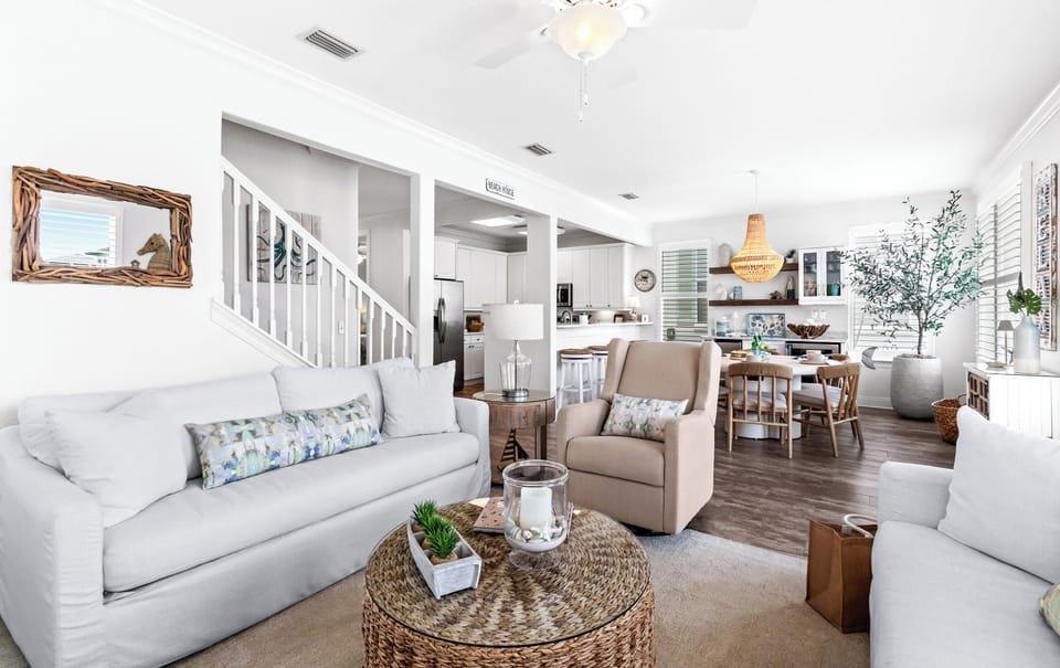 Unwind in your bright, coastal-inspired living room with comfortable seating, an open layout flowing into the dining area and kitchen, and charming beach décor throughout.