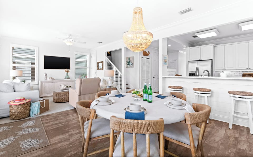 Gather around your coastal-inspired dining table while natural light pours through the open living space, connecting you to the bright, inviting kitchen where your vacation memories unfold.
