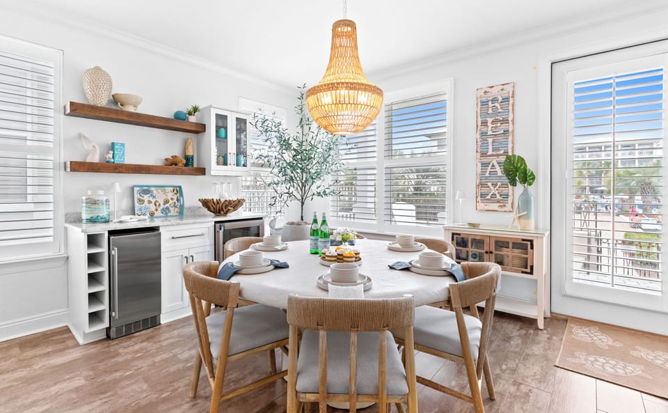 Picture yourself enjoying meals in this sun-filled dining space, where a stylish chandelier glows overhead and coastal breezes drift through plantation shutters.