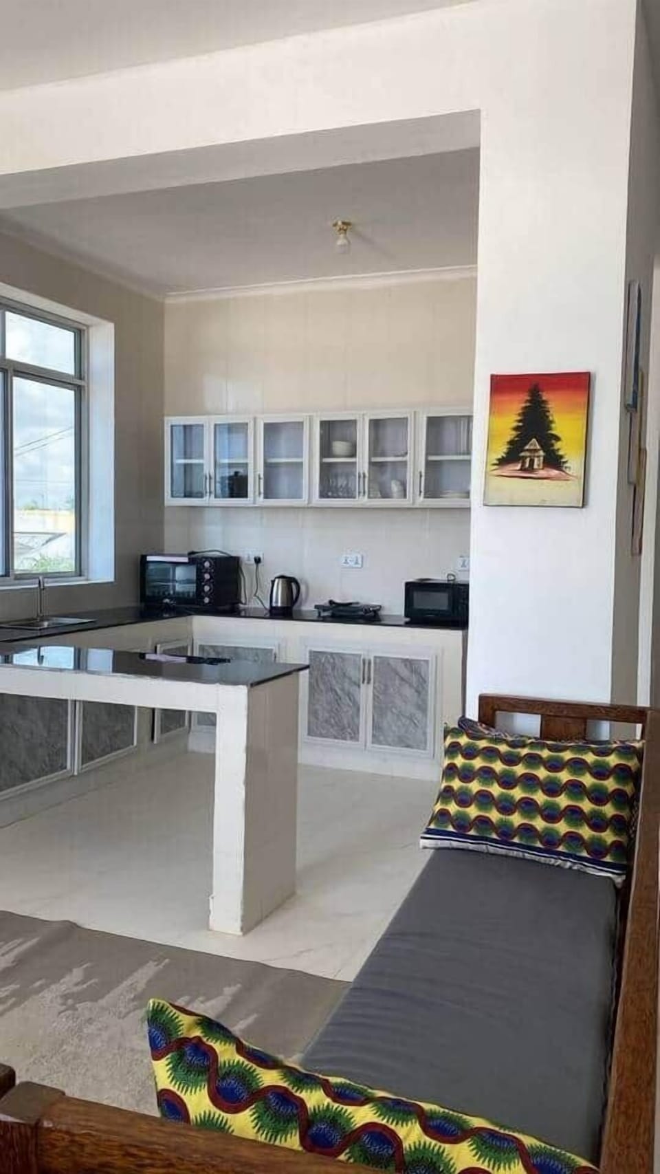 Open-concept kitchen and lounge area with natural light, colorful pillows, and modern finishes. Relax on the cozy bench while chatting with friends or prepping meals in the stylish, fully equipped kitchen.

