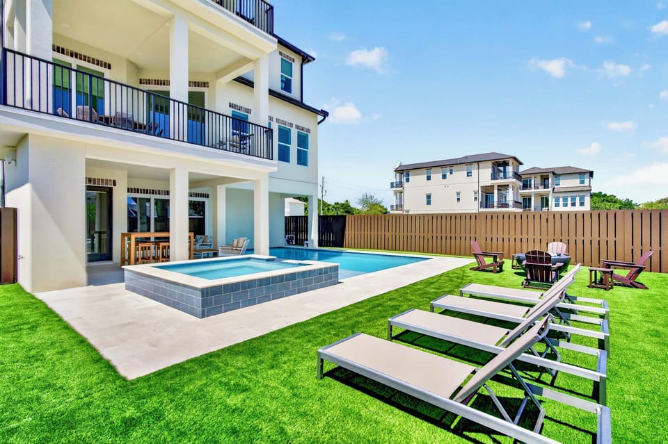 Private backyard oasis with a HEATED pool & hot tub, sun loungers, fire pit lounge, covered outdoor kitchen with gas grill, and lush manicured lawn—perfect for large group gatherings & unforgettable family vacations.