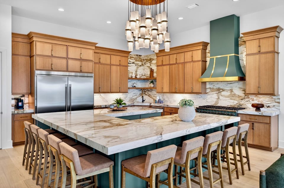 2nd Floor-Gourmet kitchen w/ oversized quartz waterfall island, seating for 10, marble backsplash, stainless commercial fridge & custom gold range hood. Perfect for large group vacations in Miramar Beach!