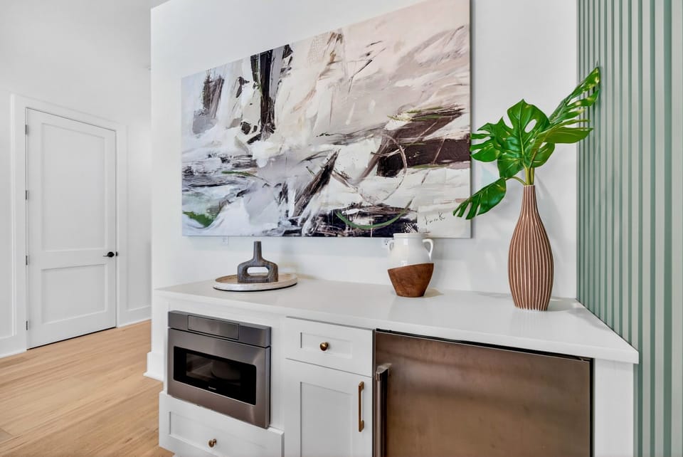 1st floor - Lounge featuring smart TV, lounge seating, marble bistro table, barn door leading to bunk room, wet bar with microwave & mini fridge—plus sliding glass doors opening directly to the pool deck for easy poolside fun.