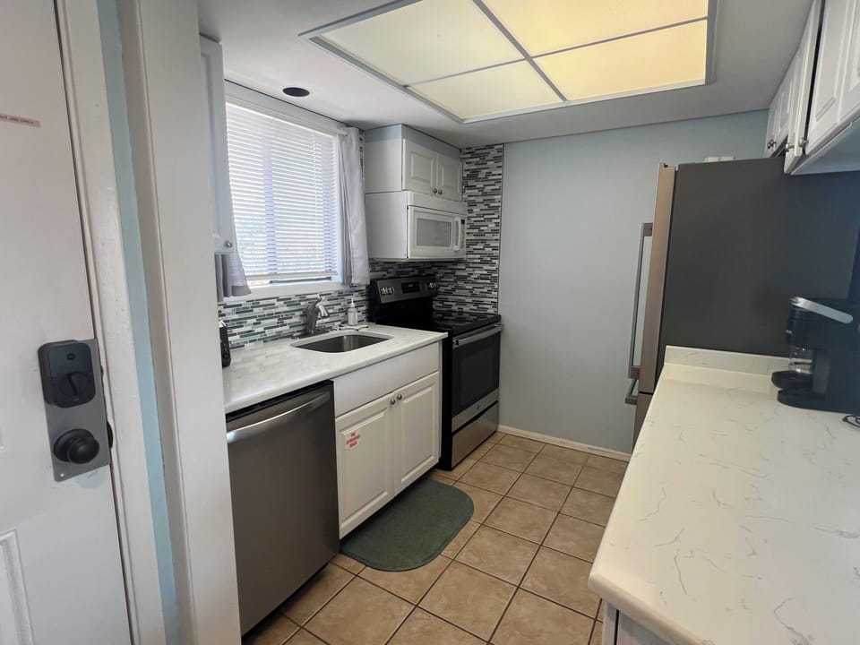 Step into your fully equipped kitchen with sleek stainless-steel appliances, stylish tile backsplash, and bright natural light—perfect for preparing your favorite meals during your stay.