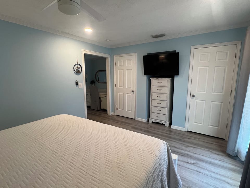 Relax in your serene bedroom with soft blue walls, a plush bed, and all the conveniences you need—including a flat-screen TV, ceiling fan, and spacious closet.