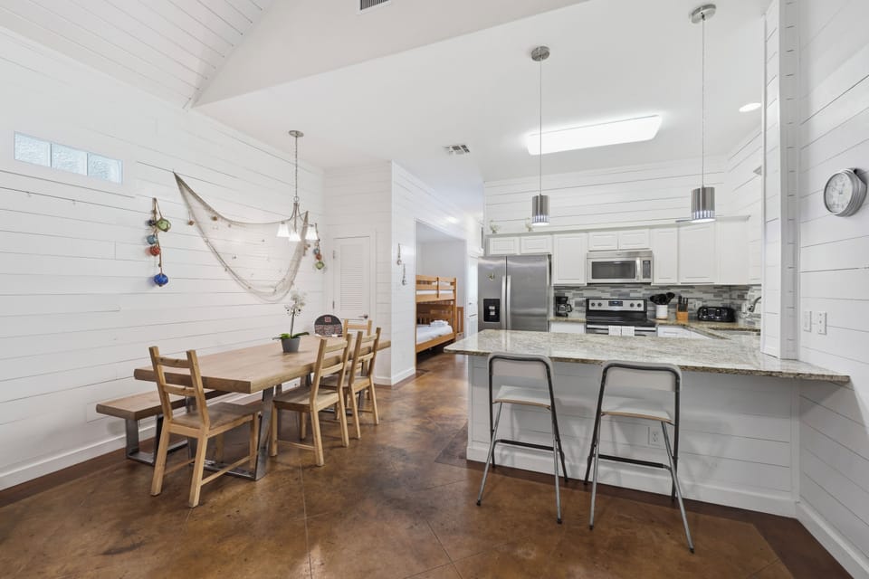 Gather around the rustic dining table or perch at the modern breakfast bar in this bright, spacious kitchen. Vaulted ceilings and coastal touches create a warm, inviting space for shared meals.