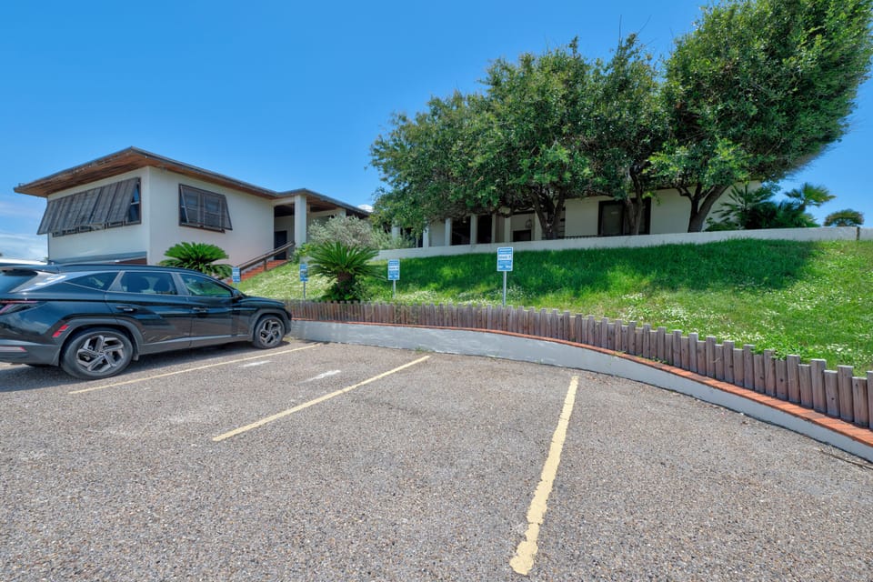 Modern beachside property with spacious parking and lush tropical landscaping under brilliant blue skies.