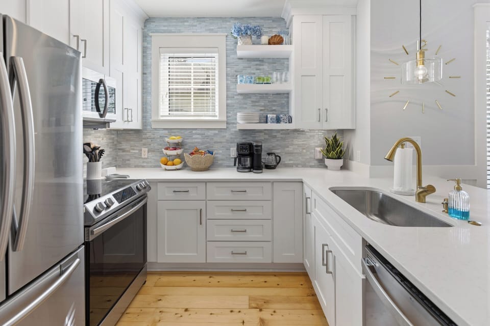 Your fully equipped kitchen features stainless steel appliances, elegant white cabinetry, and a stylish backsplash—perfect for preparing meals or enjoying your morning coffee in comfort.