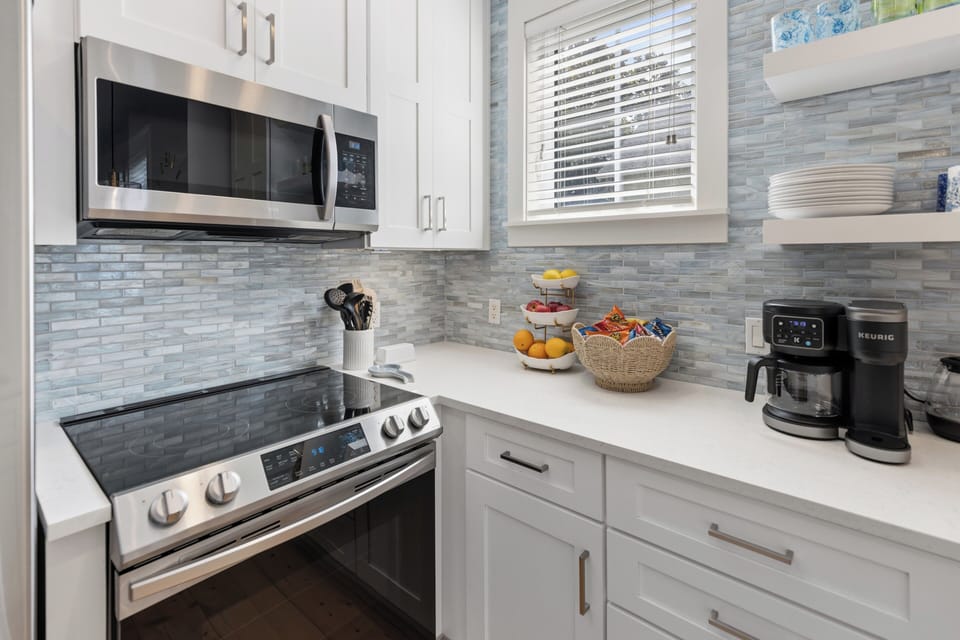Your fully equipped kitchen awaits with modern stainless steel appliances, elegant tile backsplash, and gleaming white countertops—perfect for brewing morning coffee or preparing your favorite meals during your stay.