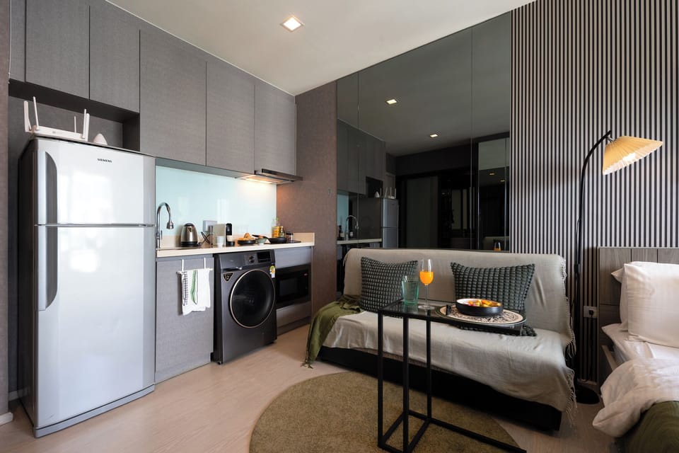 【Kitchen and Lounge Together】Sofa and TV one step from the kettle and Nespresso. Set up so the long-stay routine works without anyone moving rooms for coffee or laundry.