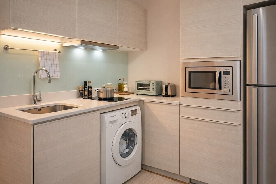 Modern compact kitchen with washer, microwave, and fridge—ideal for longer stays