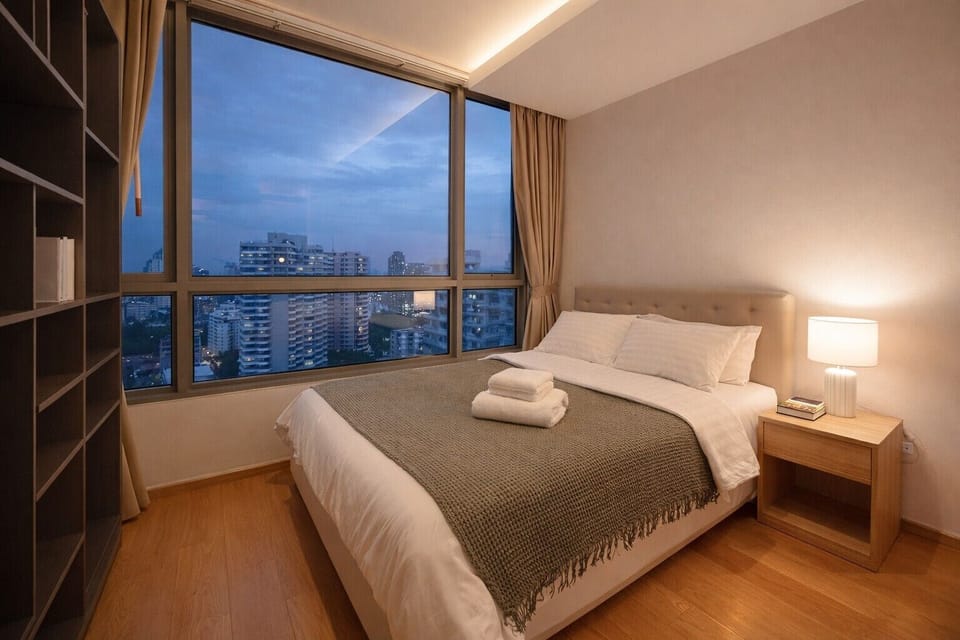 Serene city-view bedroom with queen bed, floor-to-ceiling windows and warm lighting