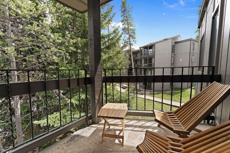 Step onto your private balcony where modern lounge chairs await, offering peaceful views of trees and greenery—a perfect spot to unwind with morning coffee or evening relaxation.