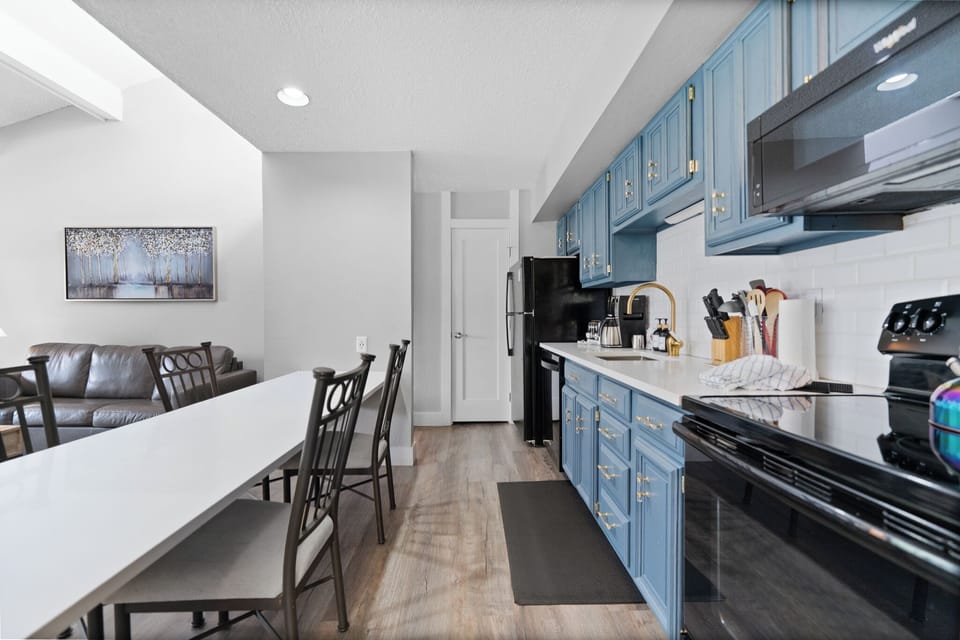You'll love cooking in this bright, fully equipped kitchen with stylish blue cabinetry, modern appliances, and ample counter space. The open layout flows seamlessly into the dining and living areas.