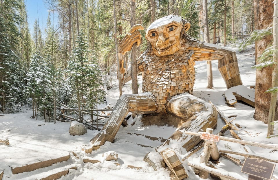 A whimsical wooden troll sculpture nestled in a snow-covered forest, offering a unique and memorable landmark near the property for winter exploration.