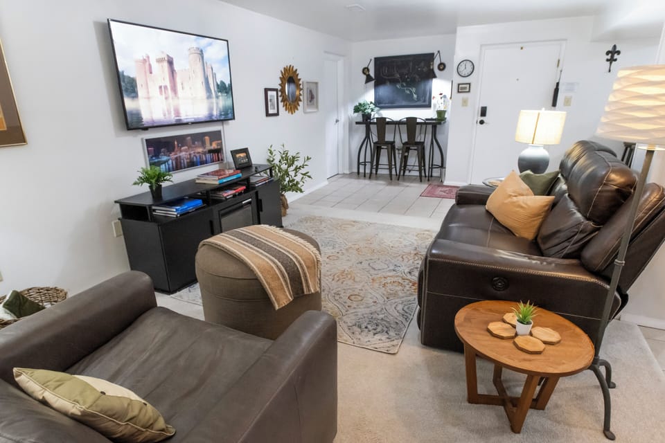 Cozy living room with leather seating, big TV, and charming breakfast bar