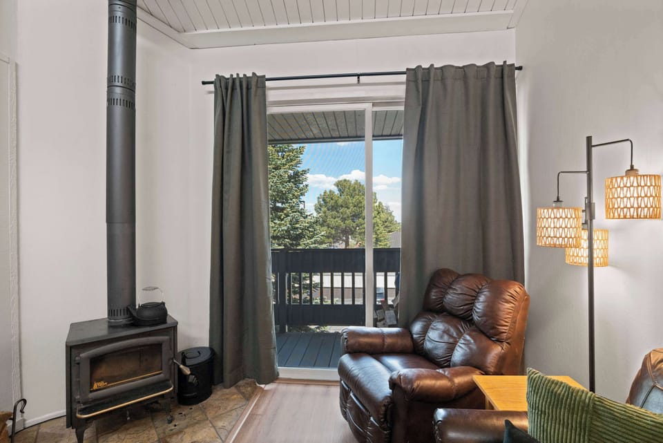 Cozy cabin living room with fire, leather, and balcony.