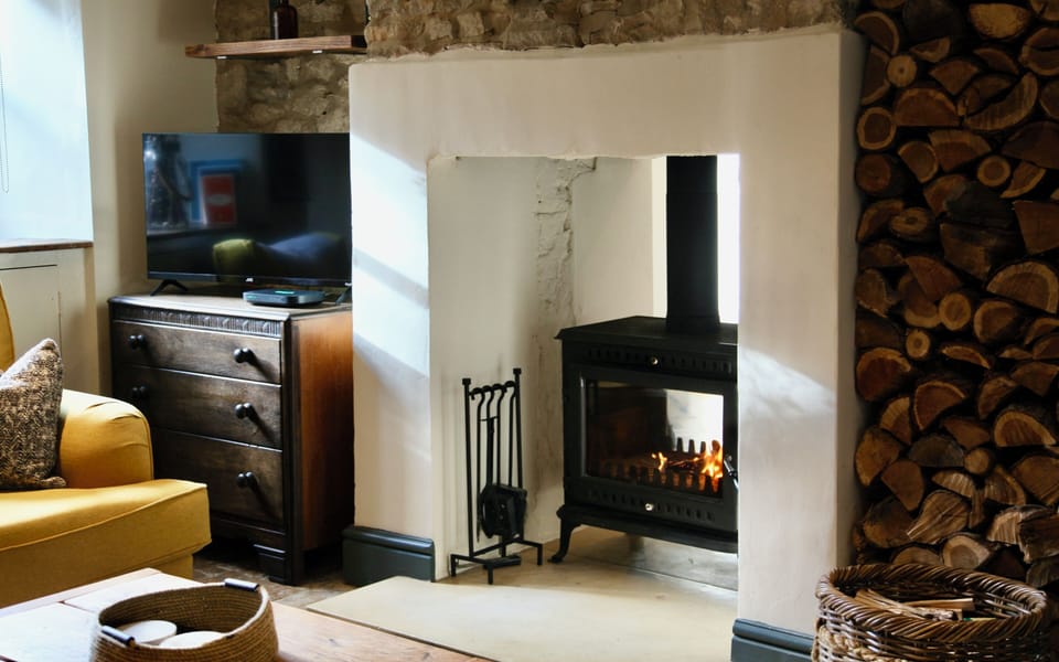 Cozy lounge with wood-burning stove, rustic charm, and warm cottage style